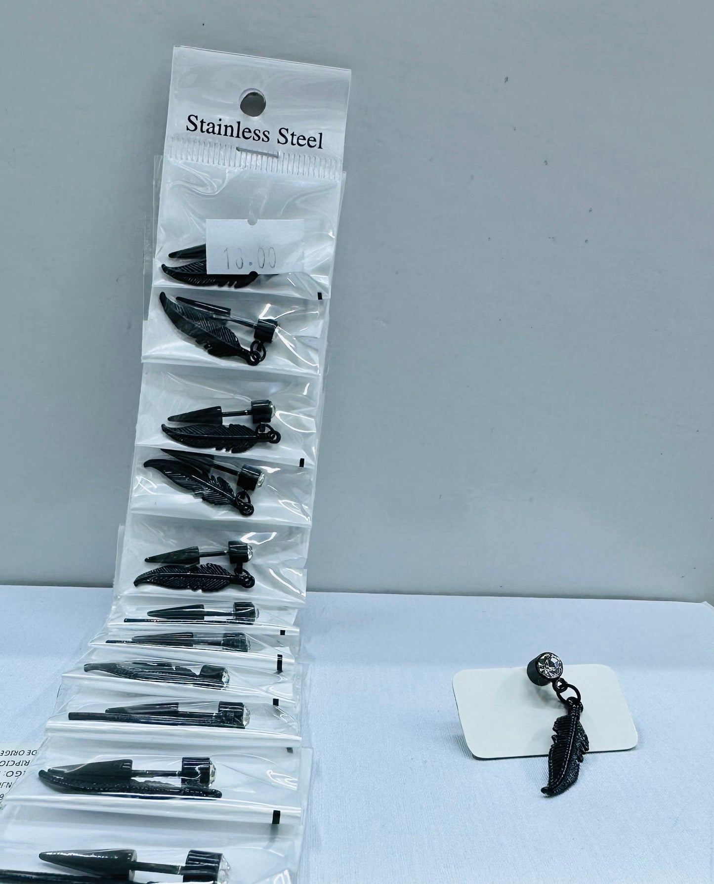 Arete solitario de varón negro con dije por 12 und.