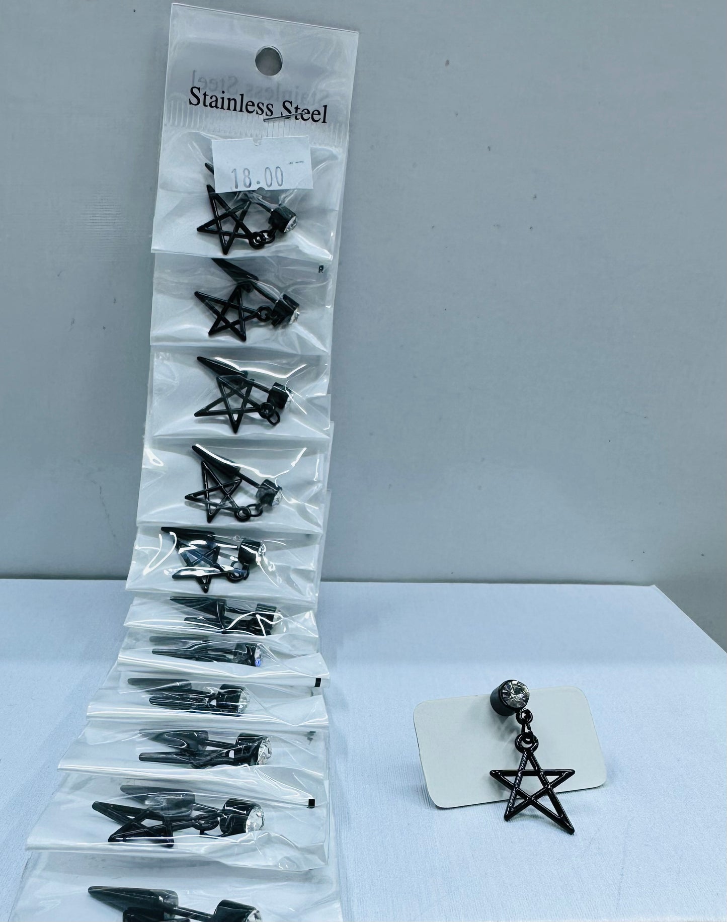 Arete solitario de varón negro con dije por 12 und.