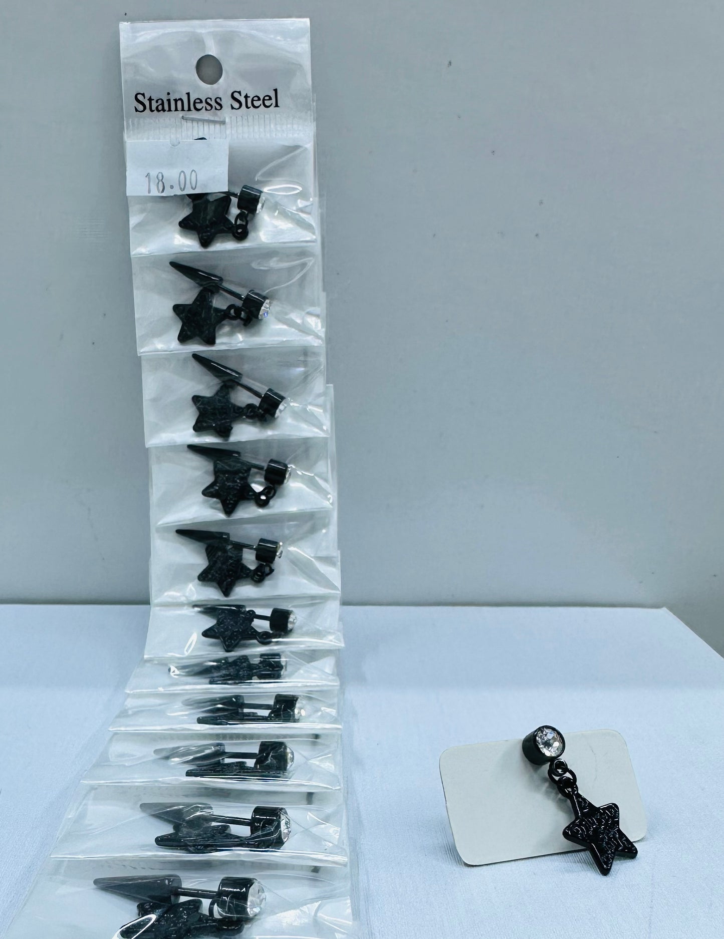 Arete solitario de varón negro con dije por 12 und.
